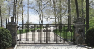 custom modern wrought iron driveway gate with geometric clean lines installed across a long tree lined driveway