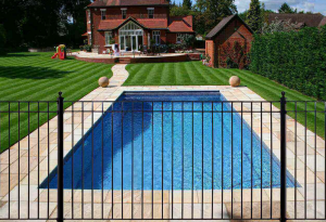 custom wrought iron pool fence with an inground pool, a large yard and a beautiful Texan home in the background