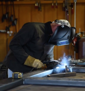 iron fabricator with welding mask and welder working on a custom wrought iron railing