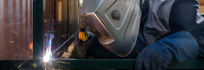 iron fabricator with welder and face shield working on wrought iron repair and restoration